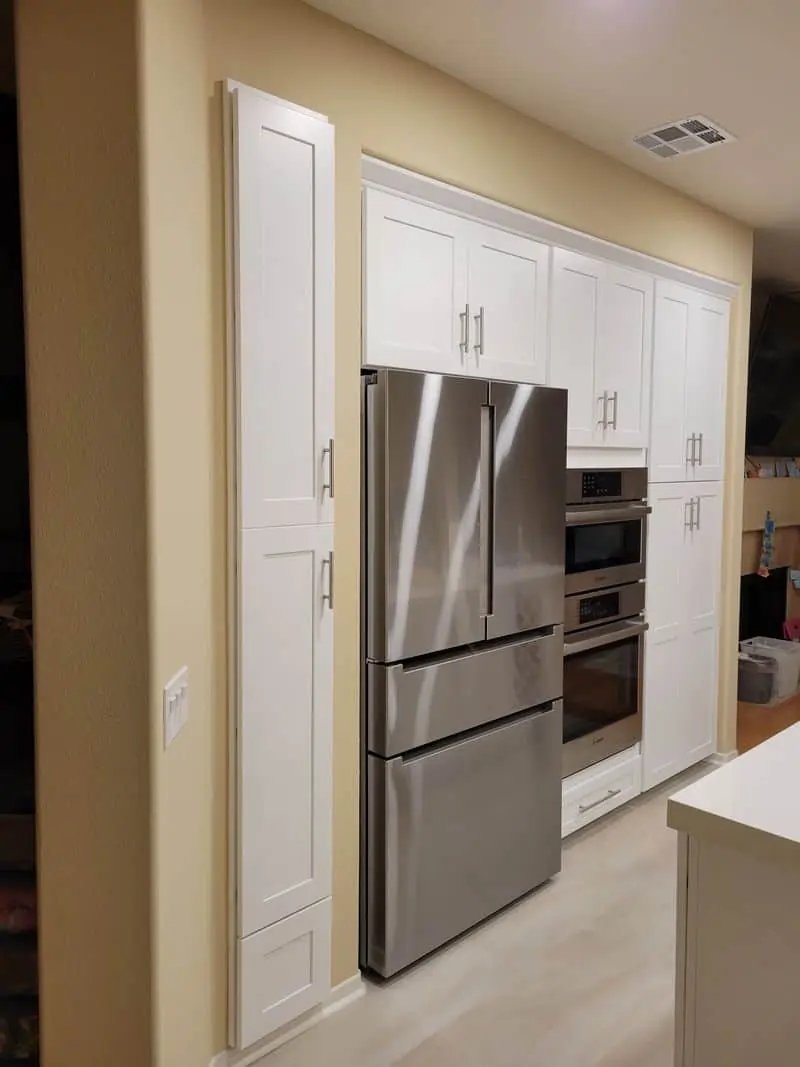 gray refrigerator built into a white cabinet