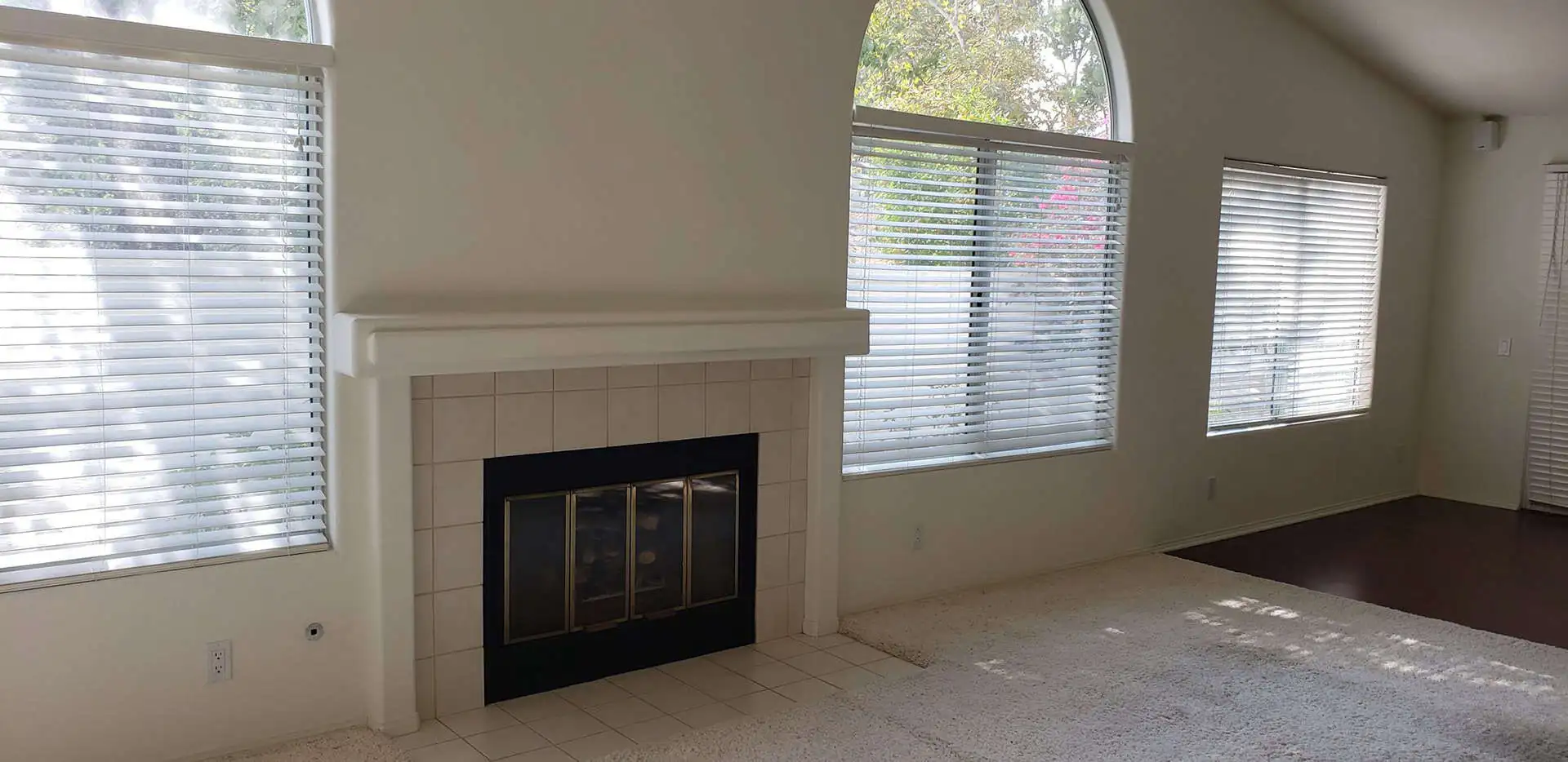a light-colored fireplace near arched windows