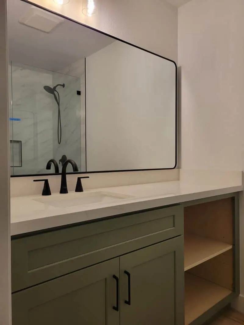olive vanity cabinet next to the mirror
